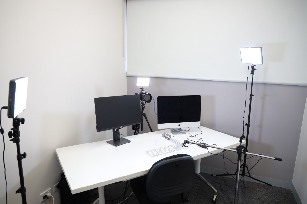 a photo of a desk with three lights and two computer monitors