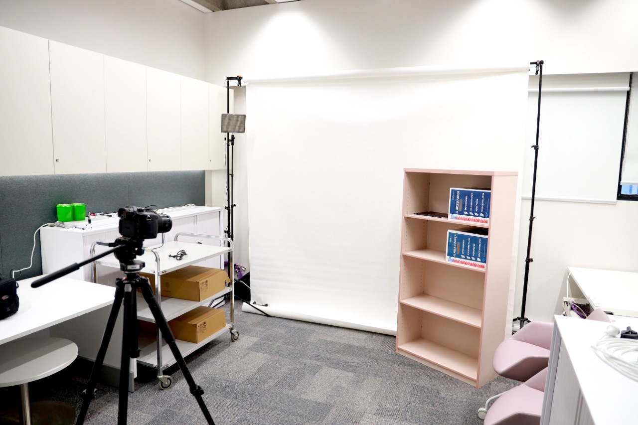 a photo of a room with a white backdrop, lighting set up and video camera on tripod